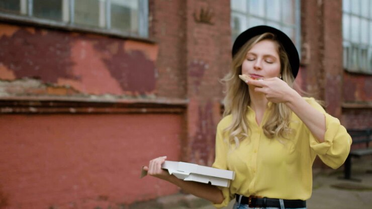 Ragazza bionda che mangia per strada.