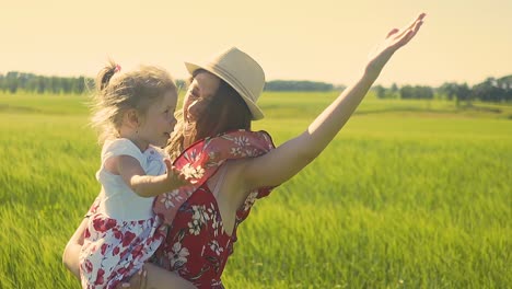 close-up slow motion young mother in red dress wearing hat she holds little daughter in her arms