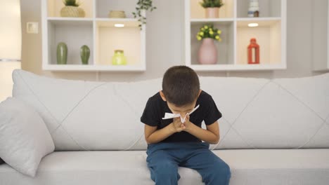 boy covering his mouth and nose with a tissue while sneezing.