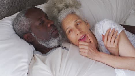 mixed race senior couple sleeping together on the bed at home
