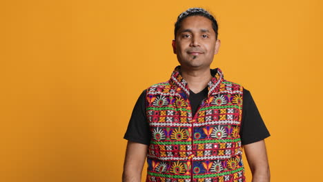 portrait of optimistic man wearing colorful vest, studio backdrop