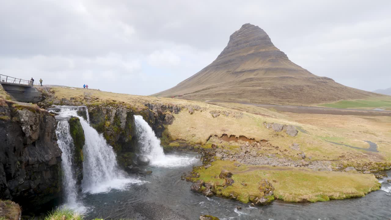 웅장한 kirkjufellsfoss 폭포와 kirkjufell 산을 배경으로, 관광객들이 아름다운 아이슬란드 풍경을 탐험합니다.