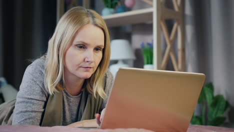 a middle-aged woman uses a laptop on her bed 5