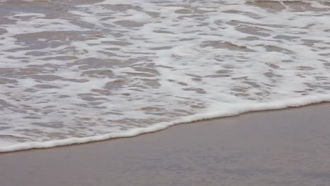 Lapping-waves-on-shoreline-with-bubbling-foam-as-the-ocean-water-ebbs-and-flows