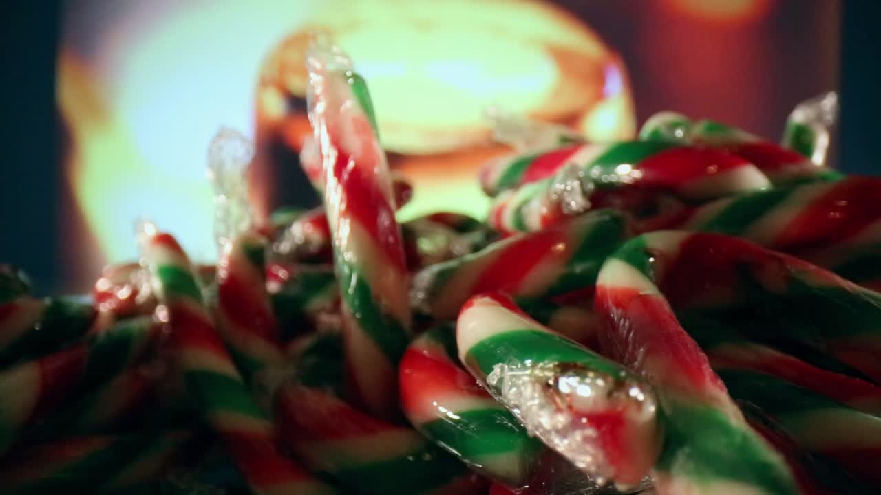 배경이 다른 색상으로 순환되는 동안 포장된 빨간색, 흰색, 녹색 미니 사탕 지팡이 더미를 향해 이동합니다.