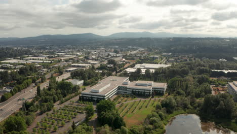 Circling-aerial-shot-around-an-office-building-next-to-a-freeway