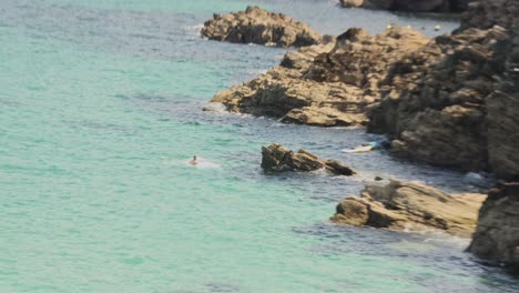 Hand-held-shot-of-a-man-backflipping-off-a-rock-into-the-sea-at-Newquay