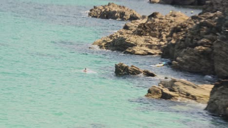 Toma-En-Mano-De-Un-Hombre-Dando-Una-Voltereta-Hacia-Atrás-Desde-Una-Roca-Hacia-El-Mar-En-Newquay.