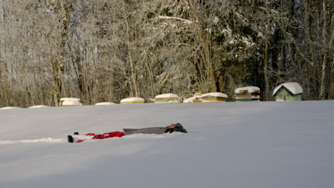 happy woman falling on her back in the snow making angel wings