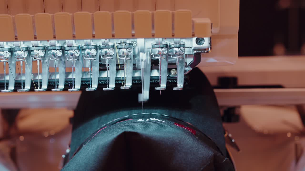 automated embroidery machine stitches detailed patterns onto black textile surface