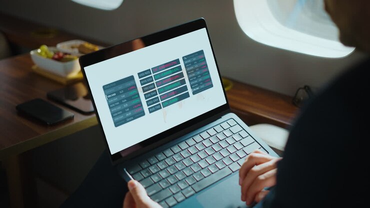 Man working on laptop with financial data in private jet