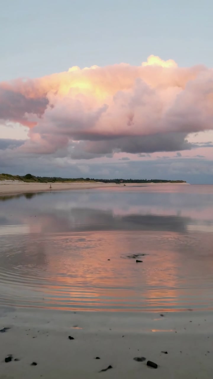 Vertical video: Shimmering cloud and reflection rippling on tidal flat after small splash appearing
