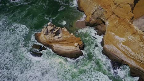 top down tilt view over la catedral rock with ocean waves crashing against the rocks below, peru, south america