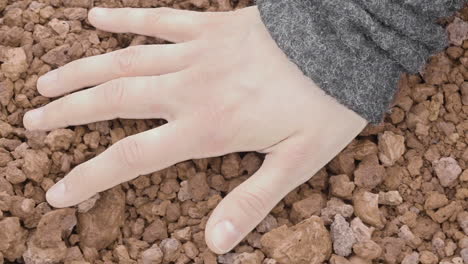 primer plano de la mano de una mujer tocando sensualmente la grava volcánica