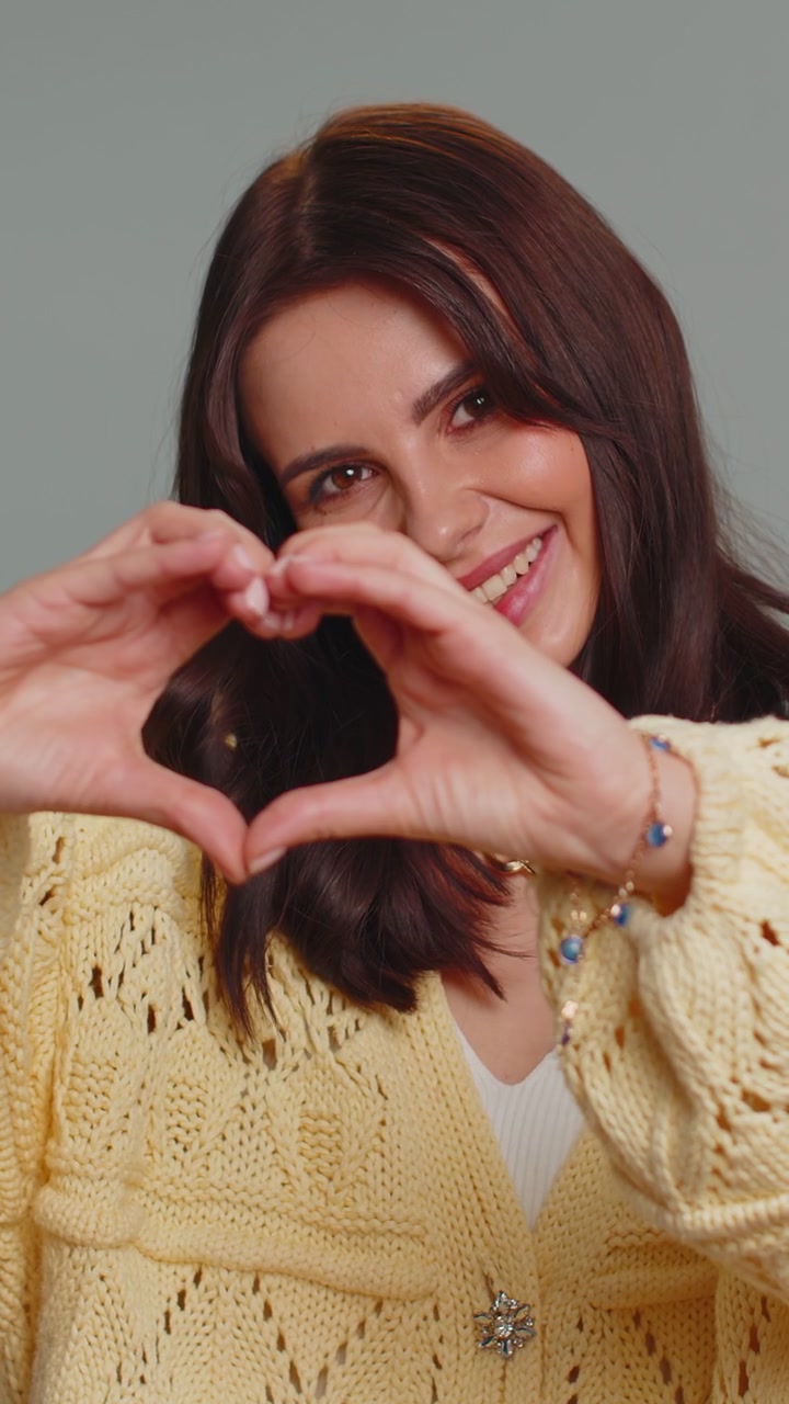 Una mujer sonriente hace un gesto de corazón demuestra un signo de amor expresa buenos sentimientos y simpatía