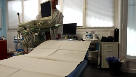 médico moviendo la máquina de ultrasonido en la clínica y hablando con alguien
