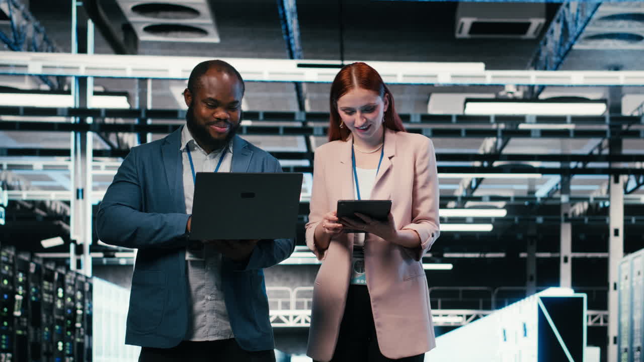 Uomo e donna tecnici IT afroamericani che collaborano in un data center.
