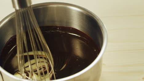 closeup white icing mixing with melted chocolate in slow motion