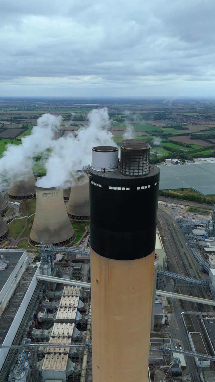 Drone aerial footage of huge power plant near Drax UK showing cooling towers, chimneys, smoke plumes and pylons in industrial energy generation scene