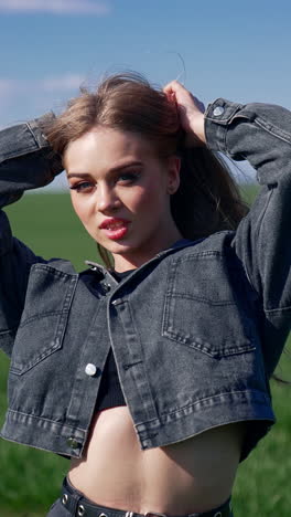 portrait of a sexy model outdoors. beautiful young woman posing on camera on the background of green field. attractive girl in the countryside. vertical video