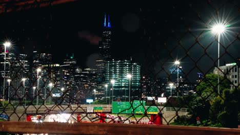 el lapso de tiempo de la ciudad urbana de chicago a través de la valla de la red metálica por la noche