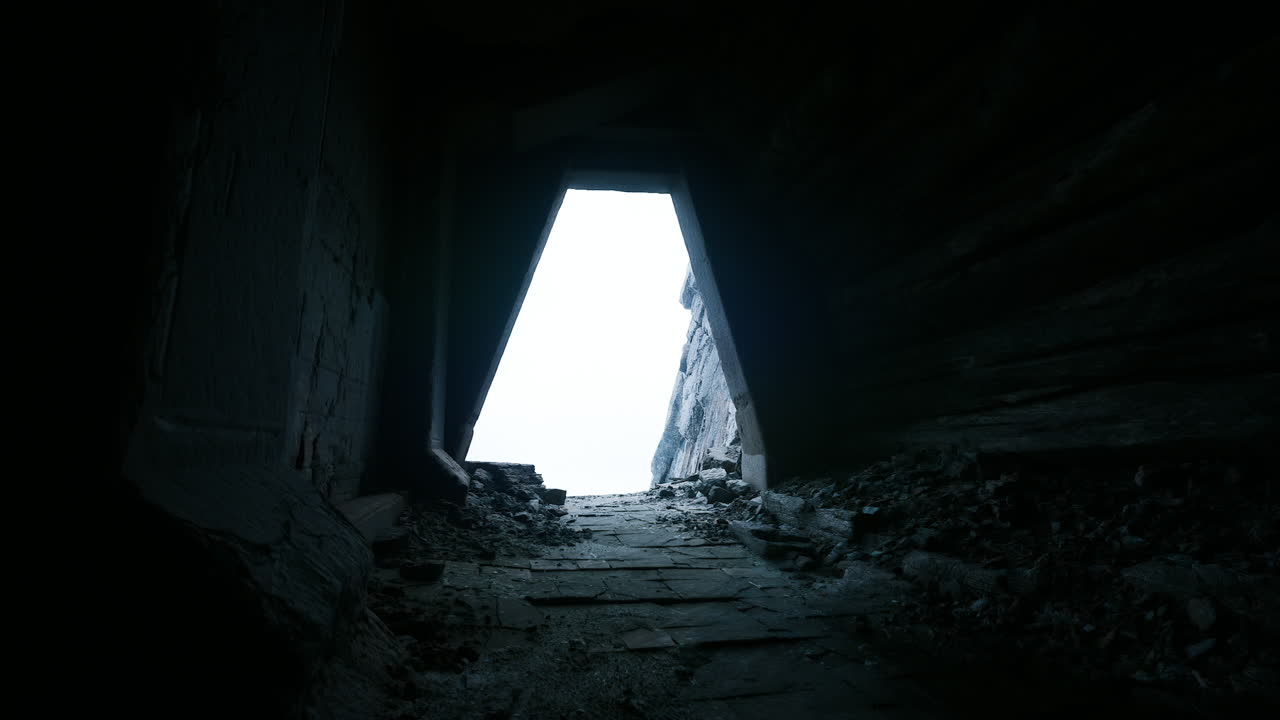 A narrow passageway leads to a bright light in an ancient building