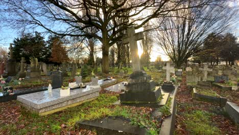 panning across cemetery at sunset with graves and crucifix headstone