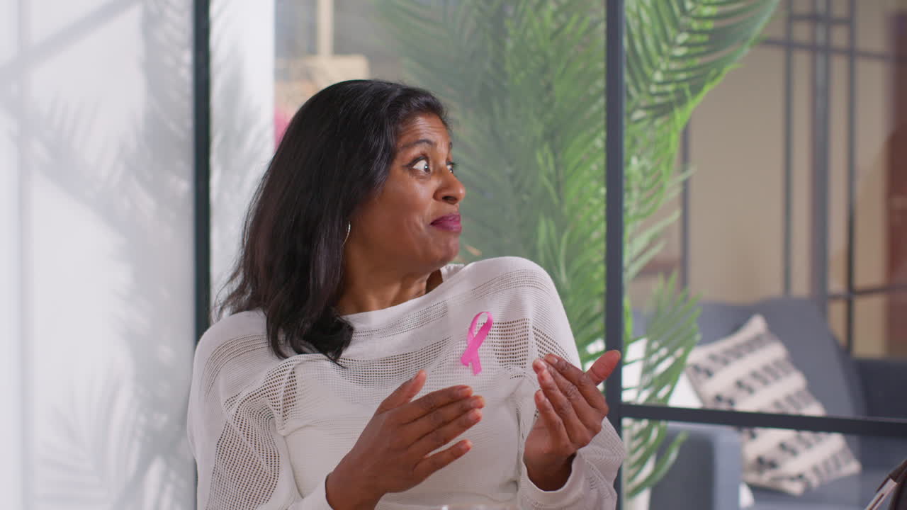 Mature Woman Wearing Pink Breast Cancer Awareness Ribbon Talking At Meeting Of Therapy Support Group For Cancer Treatment Patients 6