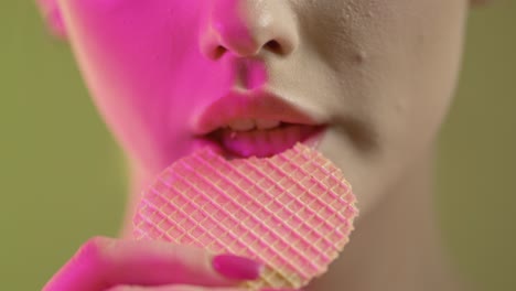 cerca de la cara y la boca de la mujer, comiendo y masticando oblea, iluminación de estudio colorida