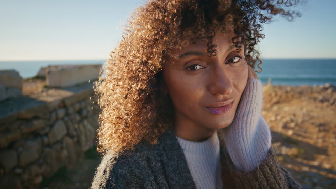 Smiling model standing ocean hill portrait. Relaxed woman posing at windy cliffs