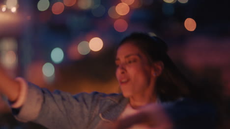 Hermosa-Joven-Sosteniendo-Bengalas-Bailando-En-La-Azotea-Por-La-Noche-Celebrando-La-Víspera-De-Año-Nuevo-Disfrutando-De-La-Celebración-Navideña