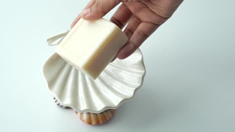 colocando jabón a mano en un plato de jabón en forma de concha de mar