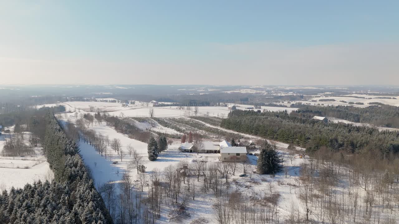 Aerial Flyover Of A Luxury House Covered By Snow In A Rural Winter Landscape At Sunrise.