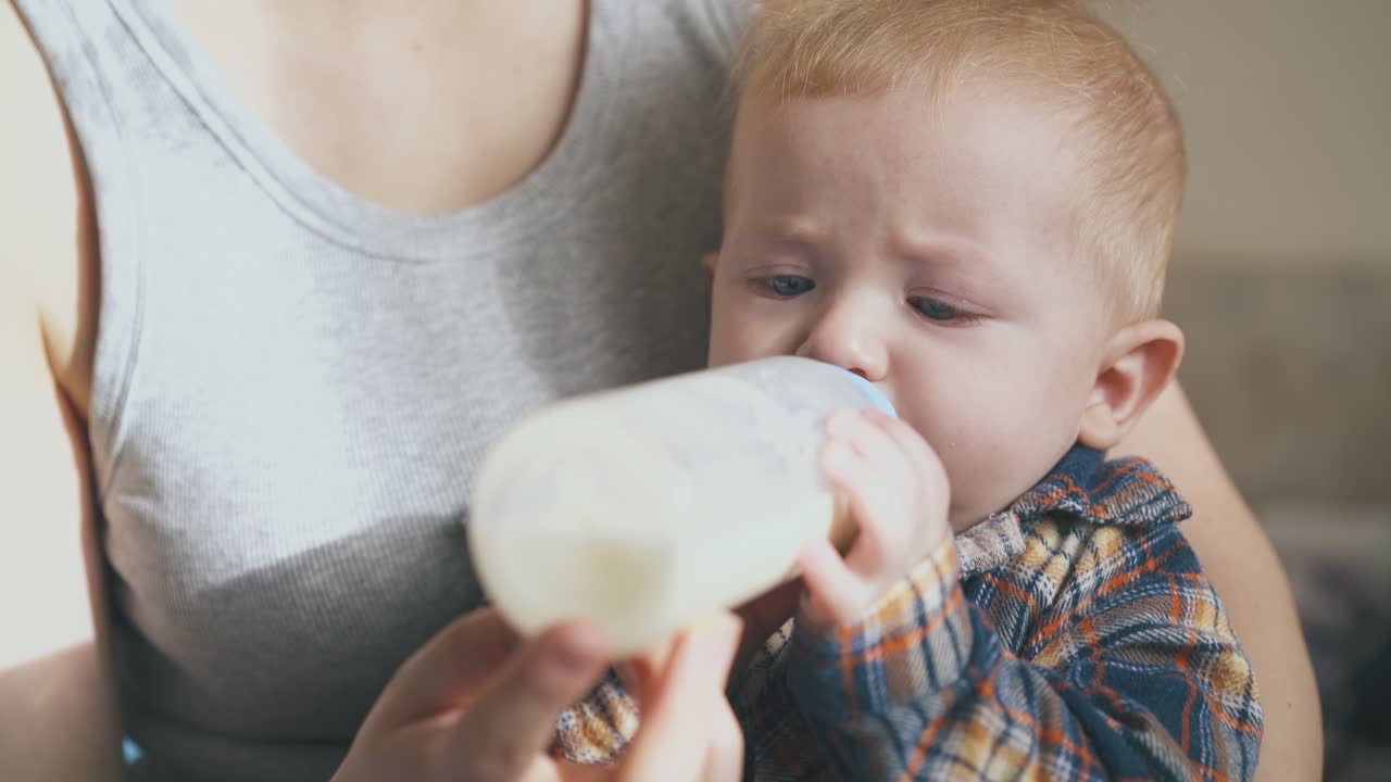 la madre alimenta al bebé con leche de la botella en una habitación espaciosa