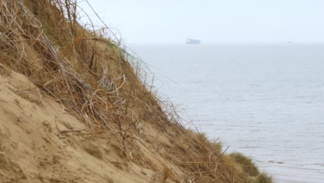 Formby-beach,-Merseyside-coastline-beach-a-ship-sails-on-the-horizon