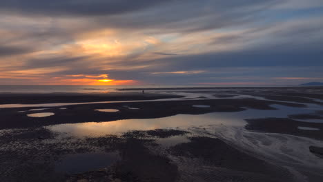 tidal pool reflections and fishermen with setting sun. lateral flight. fleetwood, lancashire, uk