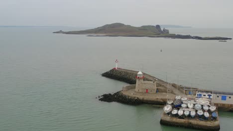 aerial pull back and ascent, revealing howth harbour's entrance