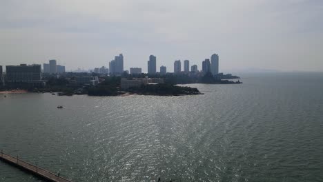 Imágenes-Aéreas-Del-Muelle-De-Pesca-De-Pattaya-Hacia-El-Santuario-De-La-Verdad-Con-Edificios-Y-Frentes-De-Playa,-Pattaya,-Chonburi,-Tailandia