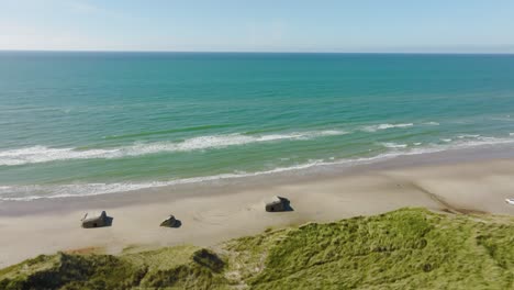 Aerial-view,-sand-dunes,-the-World-War-II-bunkers-on-a-beach,-and-views-of-the-North-Sea