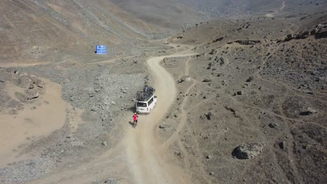 drone shot of a van with many bicycles on top of it going uphill to the start of the downhill mountain bike route