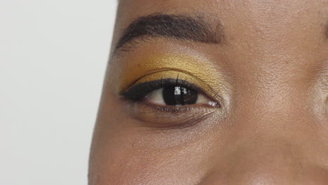 close up african american woman eye wearing makeup looking happy at camera blinking beauty cosmetics white background