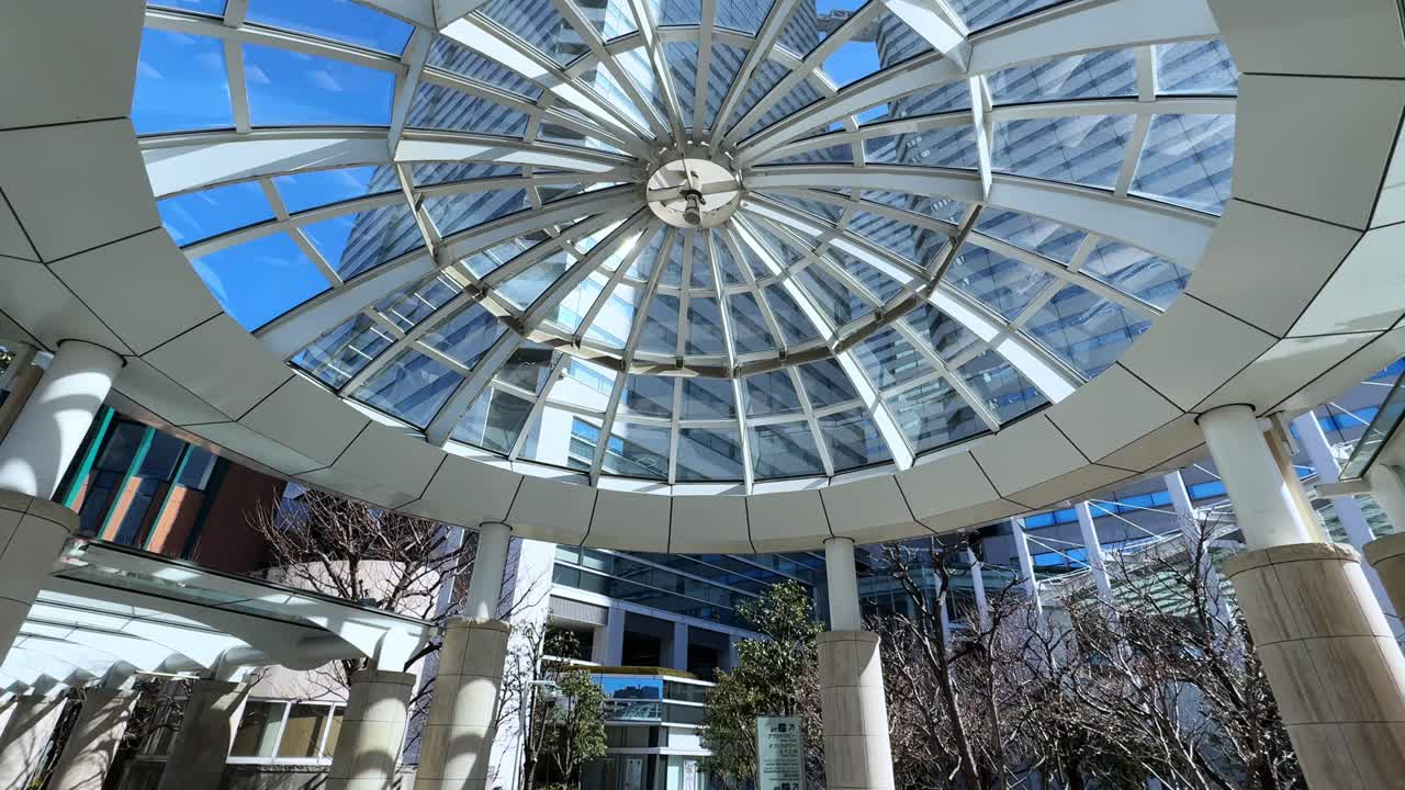 Modern outdoor walkway in Tokyo with intricate shadow patterns and glass buildings
