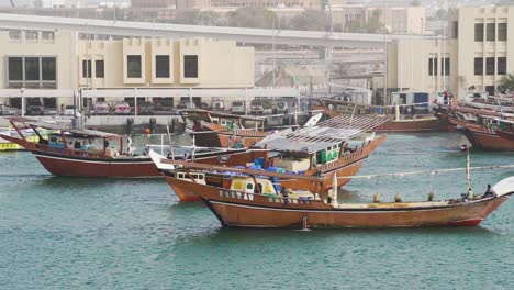 Pescadores-En-Barcos-De-Pesca-Dhow-Flotando-En-Dubai-Creek-Durante-El-Día-En-Dubai,-Emiratos-árabes-Unidos,-Oriente-Medio