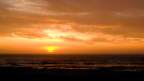 Sunset-over-ocean,-light-clouds-causing-impressive-golden-skies