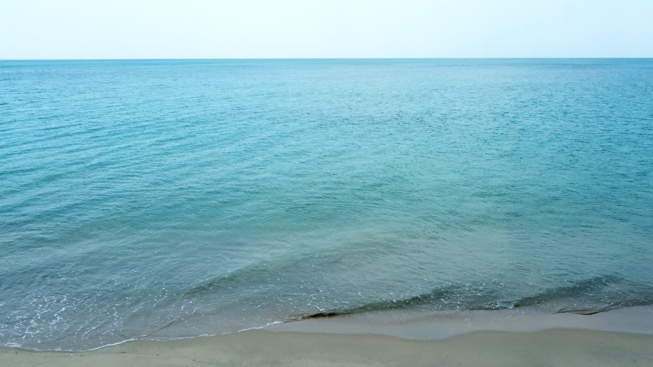 위에서 빈 모래 해변에 충돌하는 파도의 조감도