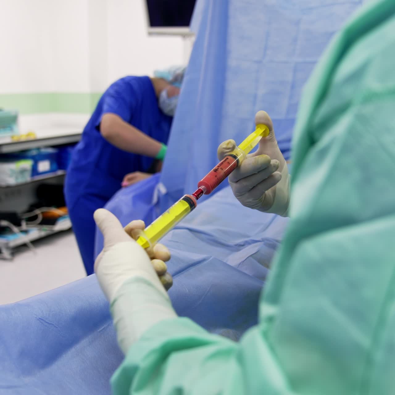 Unrecognized doctor in gloves using syringes for mixing liquids in them. Medical personnel preparing for stem cell operation at backdrop