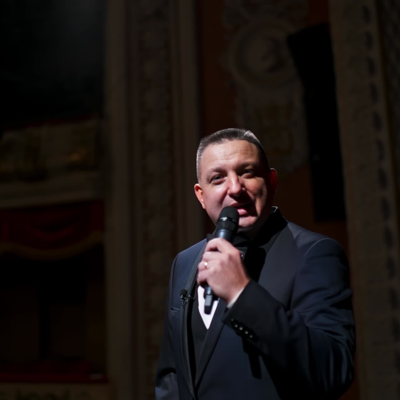 Actor with microphone announces performance before auditorium. Theater curtains background