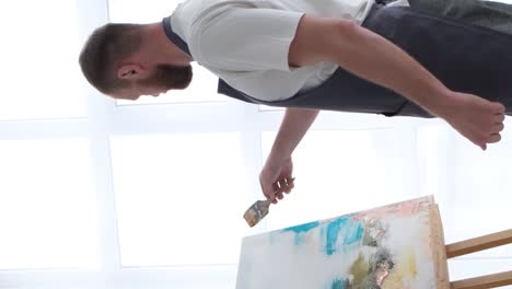 an artist paints a piece of art on a canvas with color oil painting at home an artist works and - an artist paints a piece of art on a canvas with color oil painting at home. an artist works and creatively works on an abstract oil painting in the workshop. hobby concept