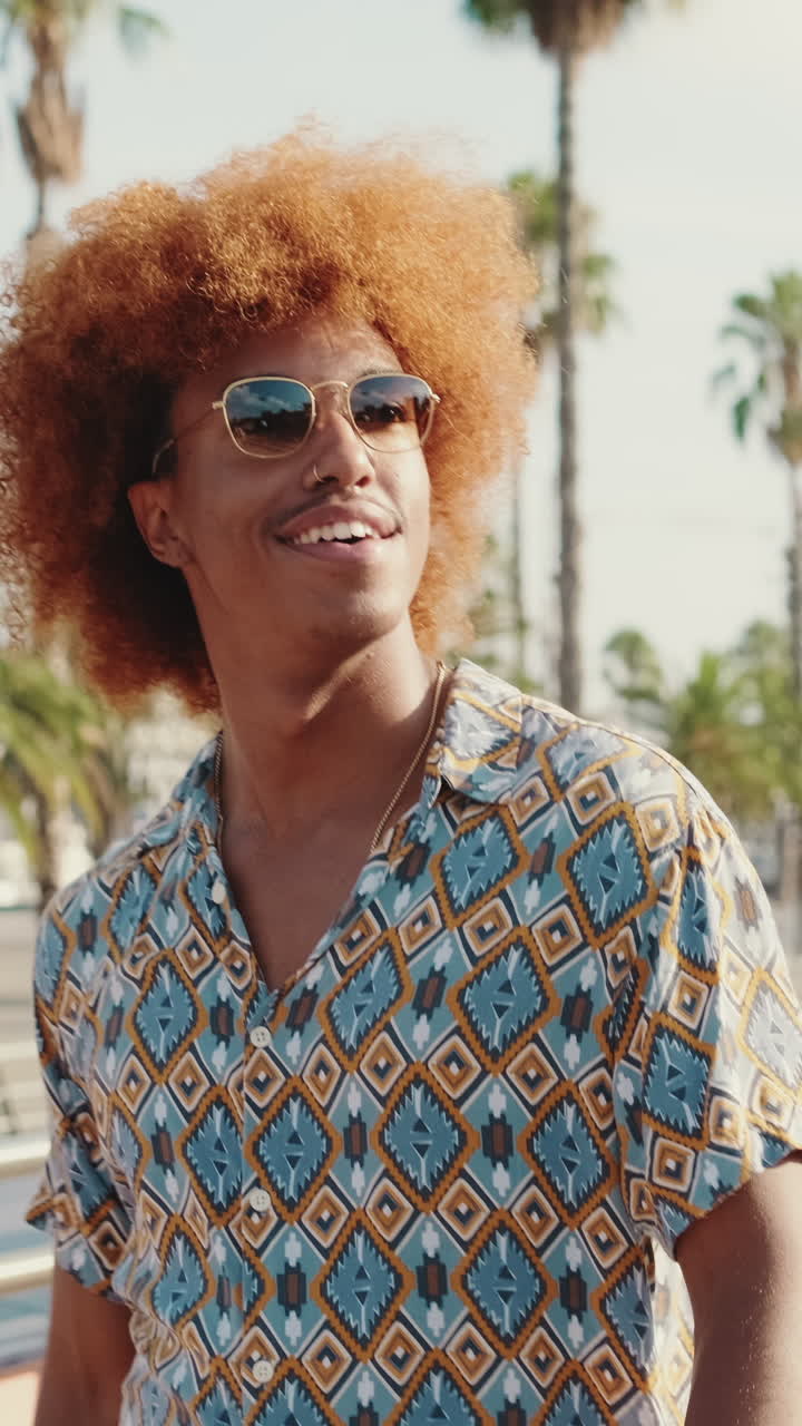 Giovane uomo felice con capelli afro che sorride all'aperto