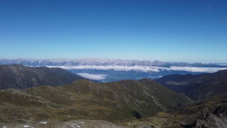 Timelapse-Aéreo-De-La-Región-Alpina-Austriaca-En-Un-Día-Soleado-De-Verano-Con-Algunas-Nubes-Blancas-Rodando-G-Sobre-El-Valle,-Frente-A-Grandes-Montañas-Alpinas-Altas